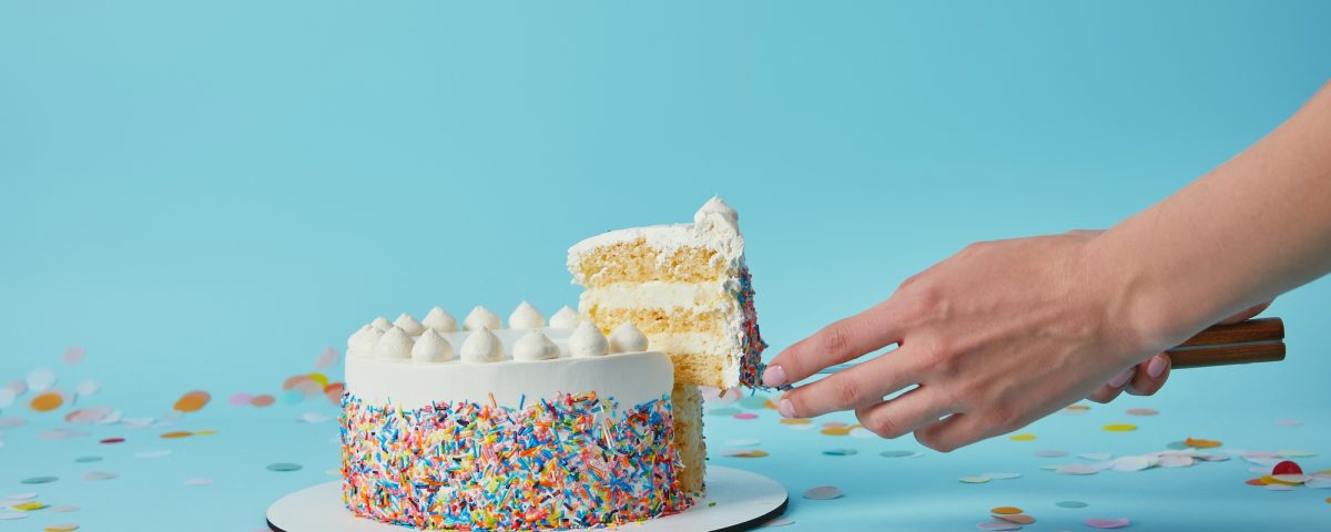 Partial view of woman taking piece of delicious cake on blue background