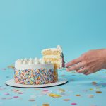 Partial view of woman taking piece of delicious cake on blue background