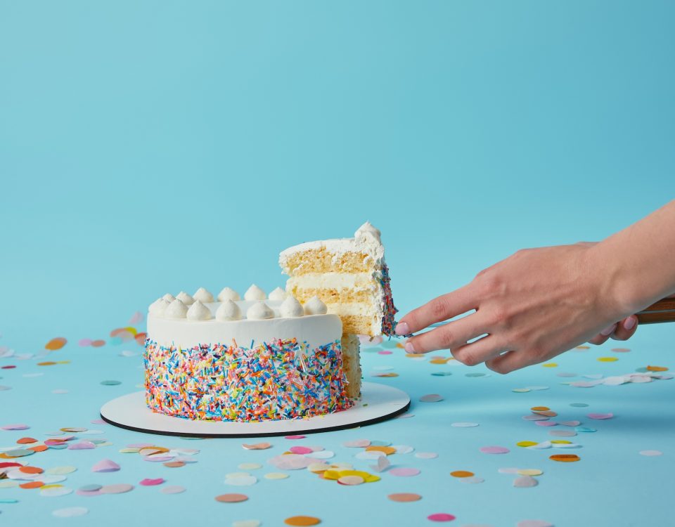 Partial view of woman taking piece of delicious cake on blue background